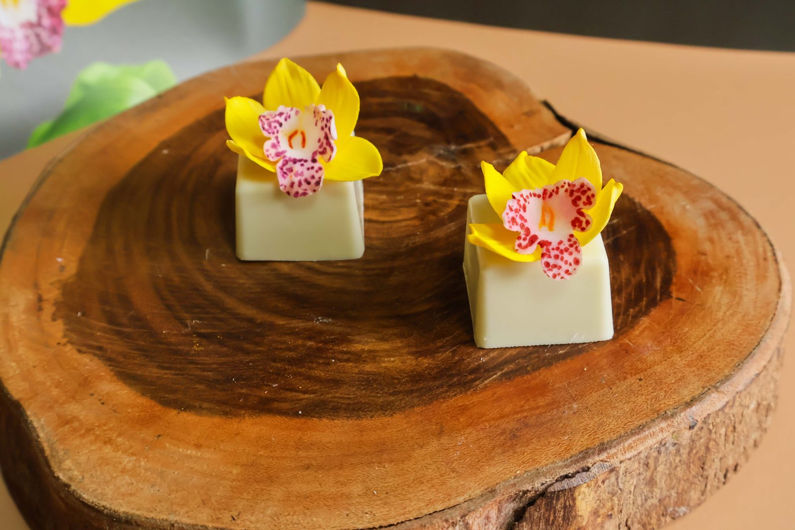 Barras de chocolate branco com orquídeas amarelas de açúcar sobre fatia de madeira
