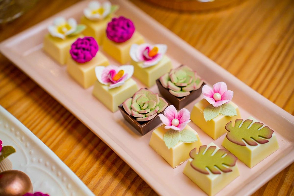 Barras de chocolate com flores e folhas de açúcar em bandeja rosa